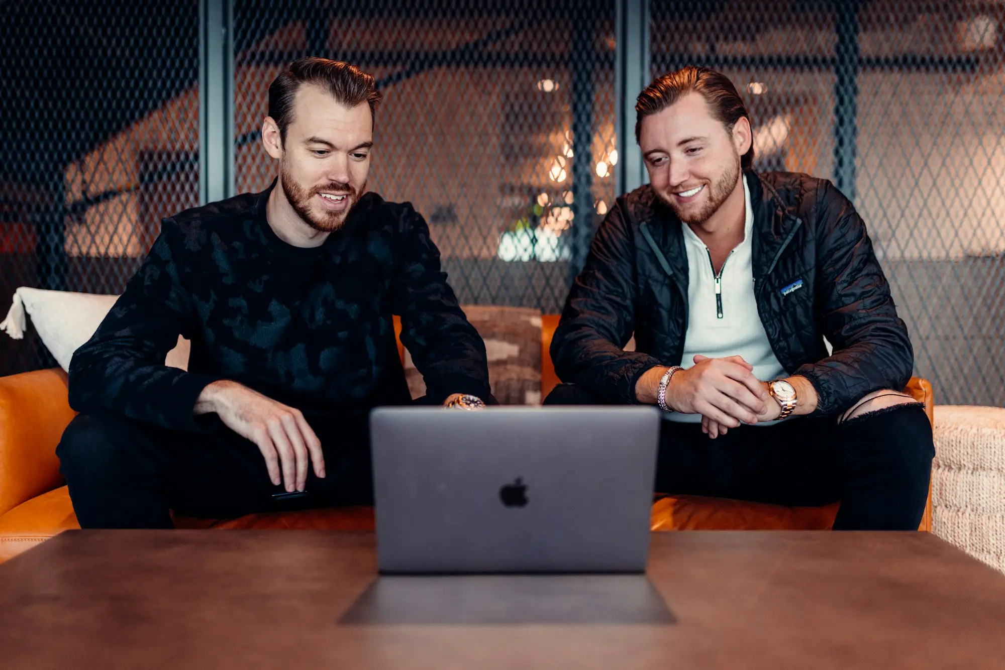 Two business partners reviewing an online store's sales dashboard on a laptop before making an offer to buy it