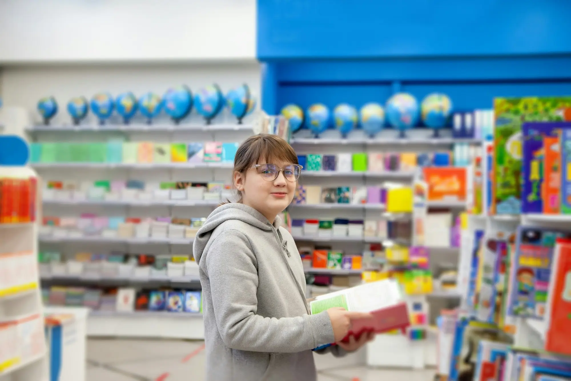 Shopper browsing a well-stocked shelf of books and stationery in a bright retail store