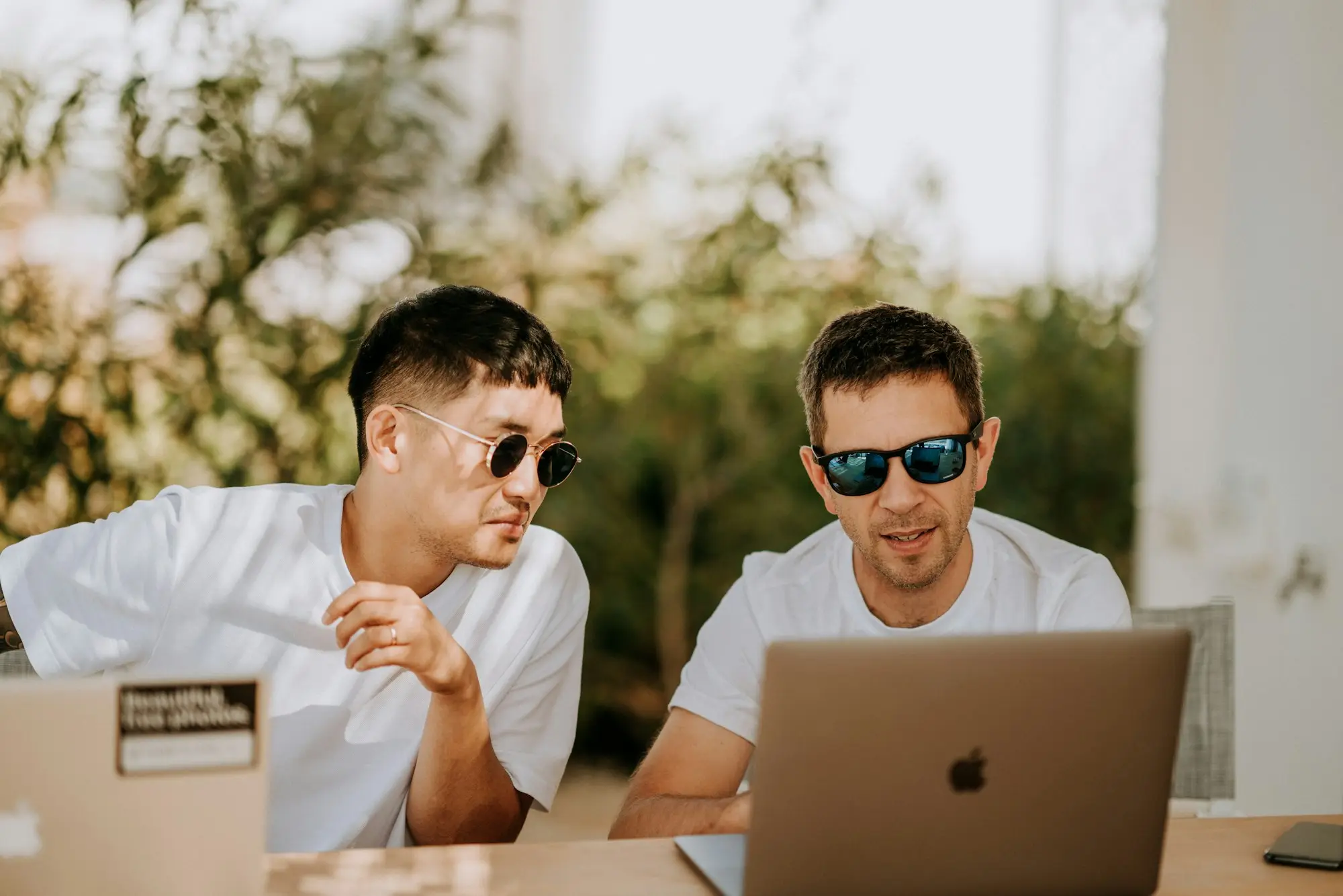 Two business partners outdoors reviewing a secured business loan application on a laptop